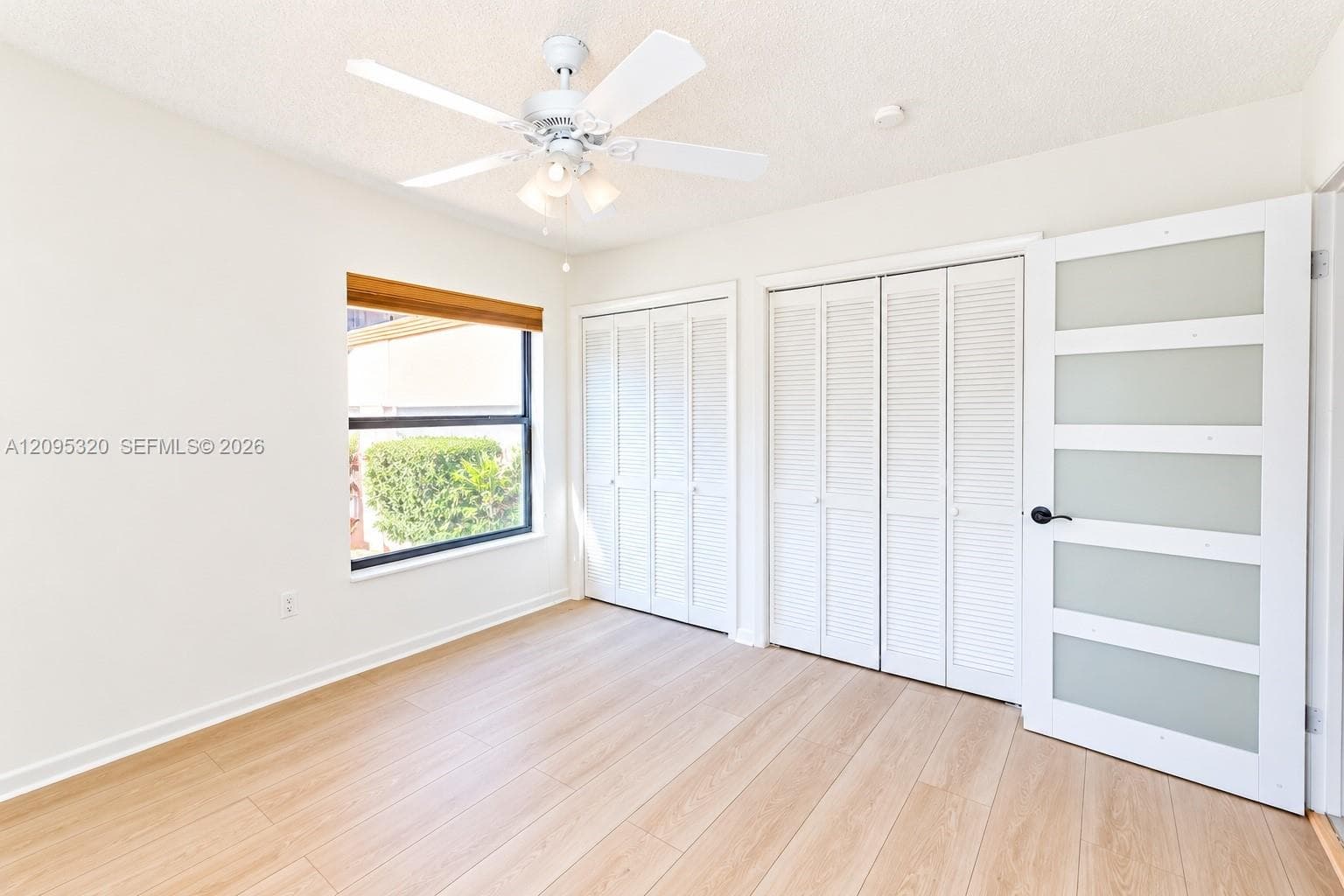 Wood-finish flooring, white walls, and a window with a wood-tone valance