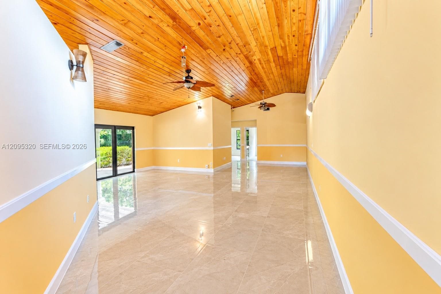 Vaulted wood-plank ceiling, tile flooring, two-tone wall treatment, and dual ceiling fans
