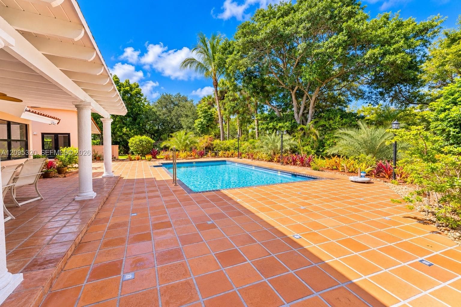 Rectangular swimming pool surrounded by a terracotta tile patio