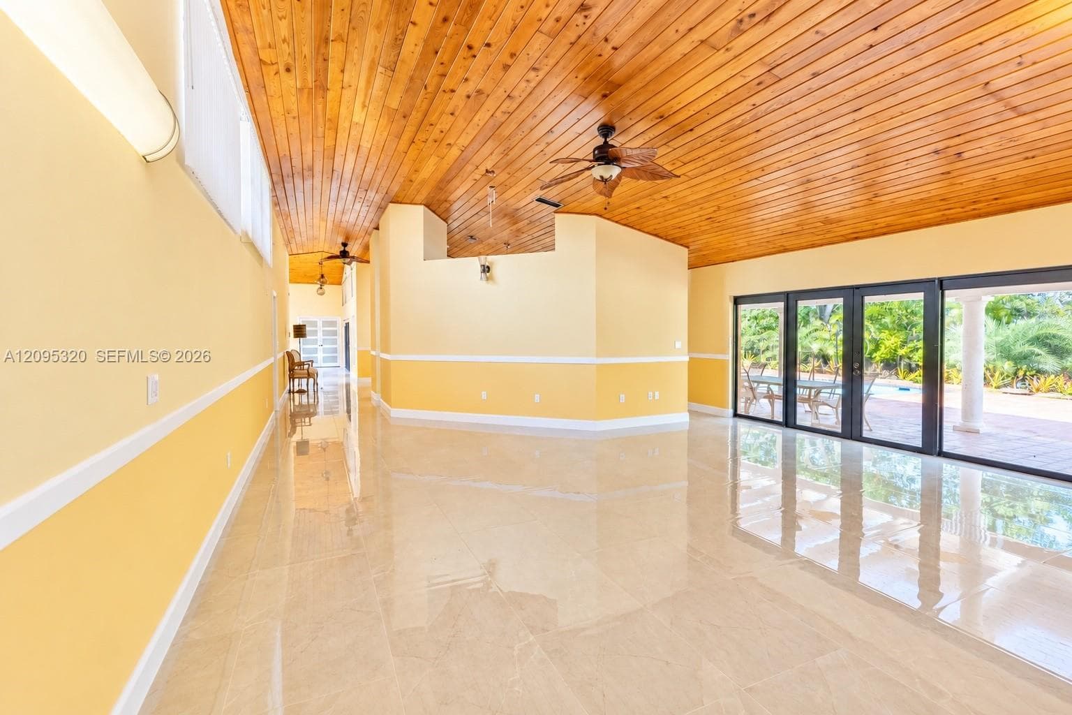 High-gloss tile flooring, wood-paneled ceiling, ceiling fan, and sliding glass doors
