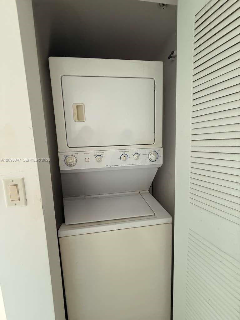Stacked laundry unit set within a dedicated recessed closet featuring a louvered door