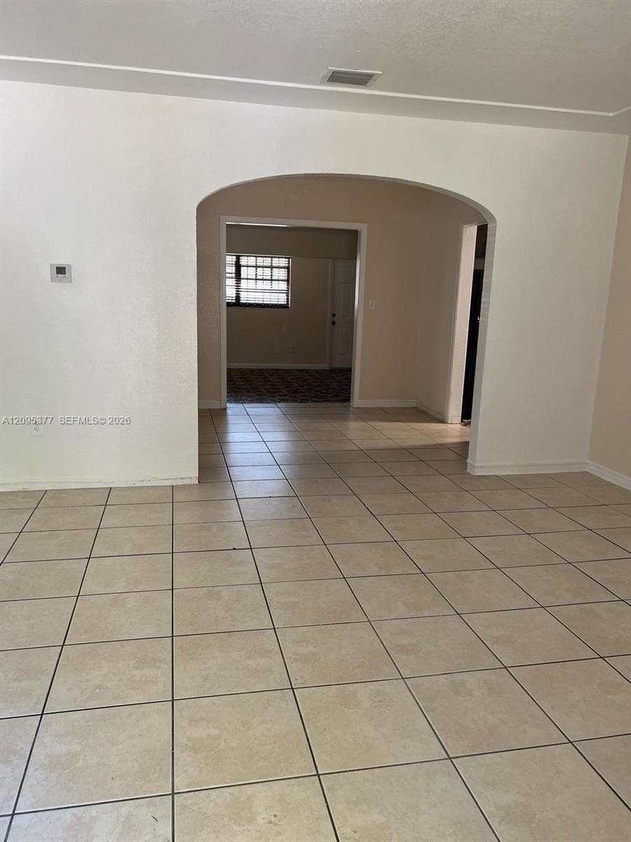 Neutral-toned tile flooring, distinctive arched architectural opening, and clean, light-colored walls