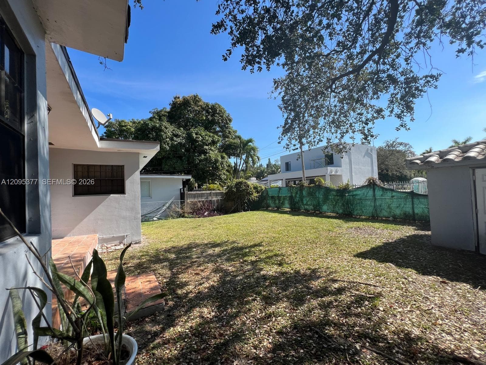Backyard featuring a grass lawn, paved patio, detached storage structure, and perimeter fencing