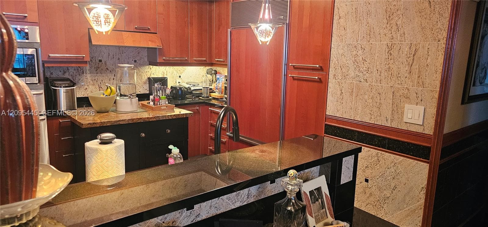 Kitchen featuring cherry-wood cabinetry, stone countertops, panel-ready refrigerator, and black metal faucet fixtures
