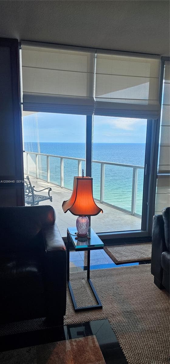 Floor-to-ceiling glass sliding doors, private balcony with glass railing, and Roman shades