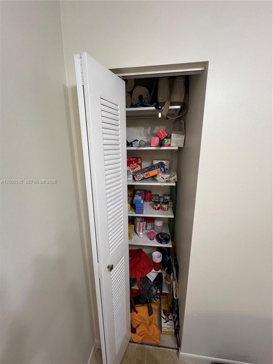 Storage closet featuring a white bi-fold louvered door and six levels of fixed shelving