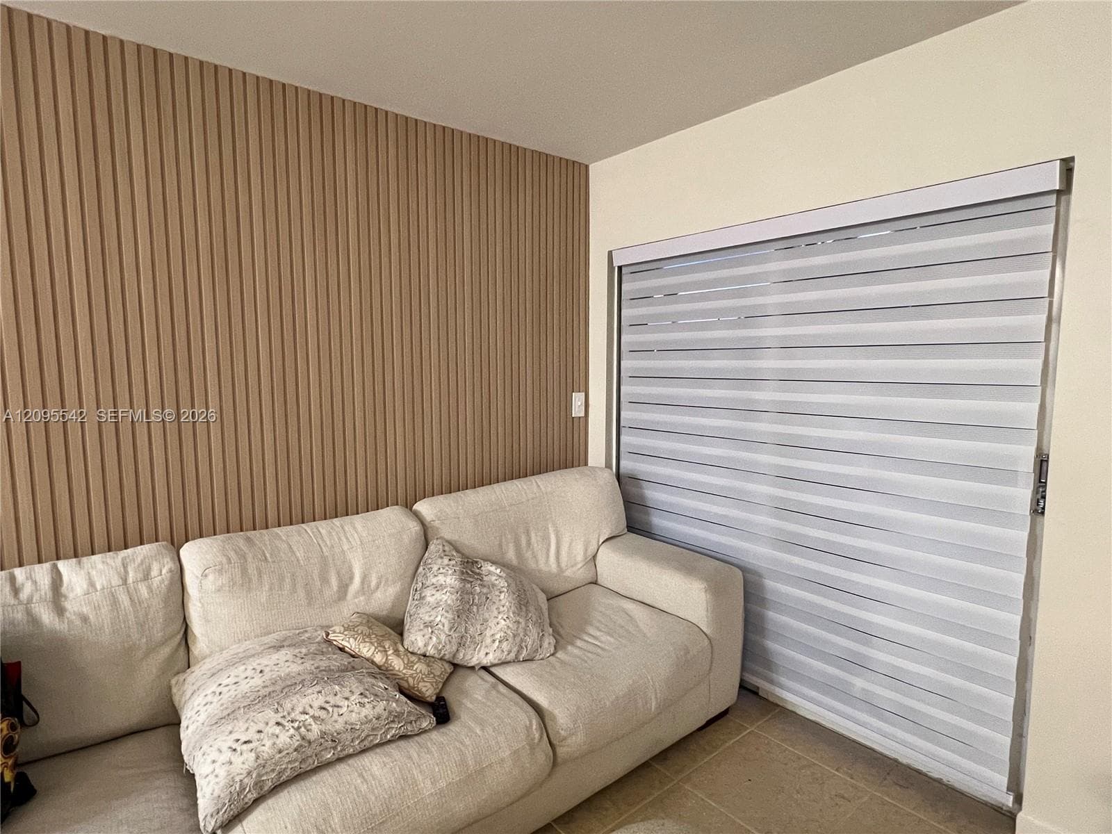 Vertical wood-slat accent wall with tile flooring and horizontal window shades