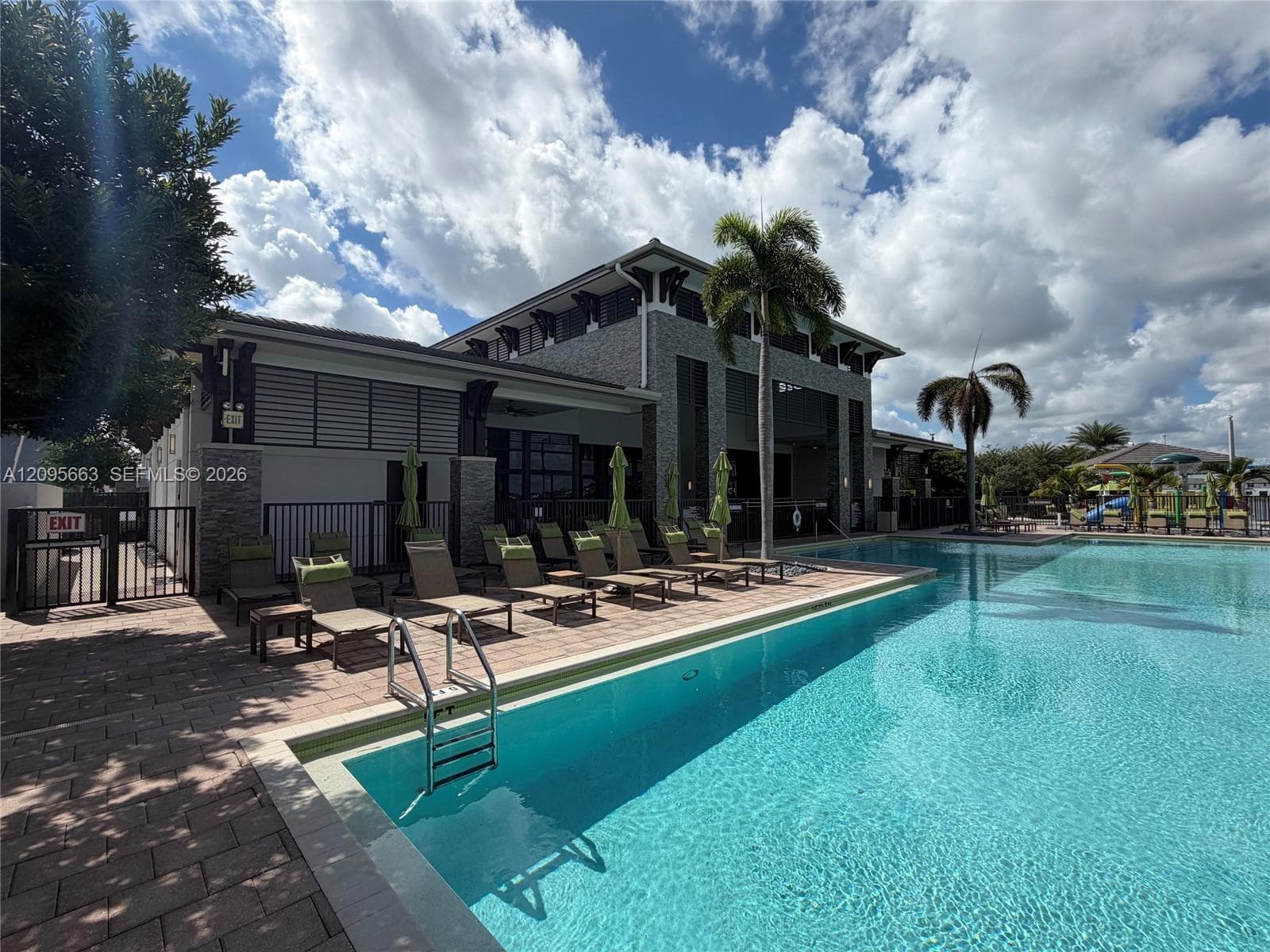 Swimming pool featuring paver decking, stone exterior accents, and covered outdoor common area