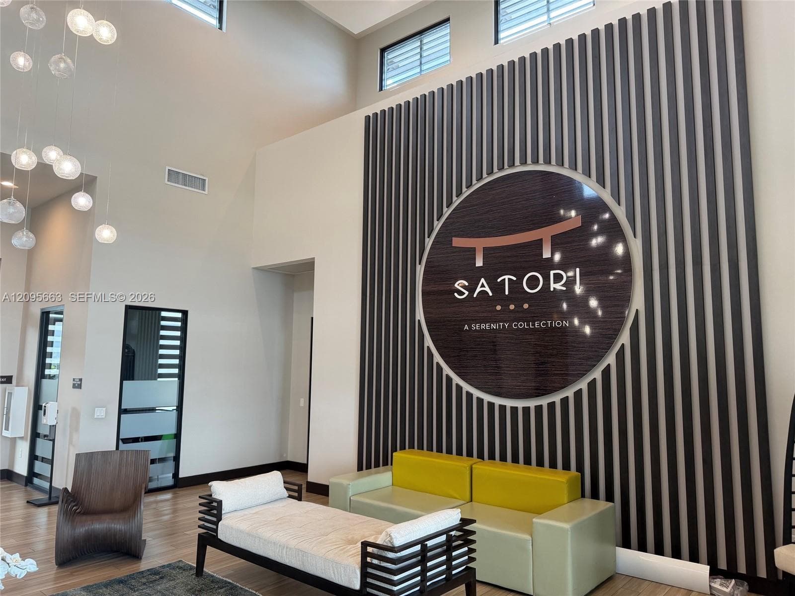 Double-height ceilings, vertical slat wall paneling, circular architectural inlay, and multi-pendant lighting fixture