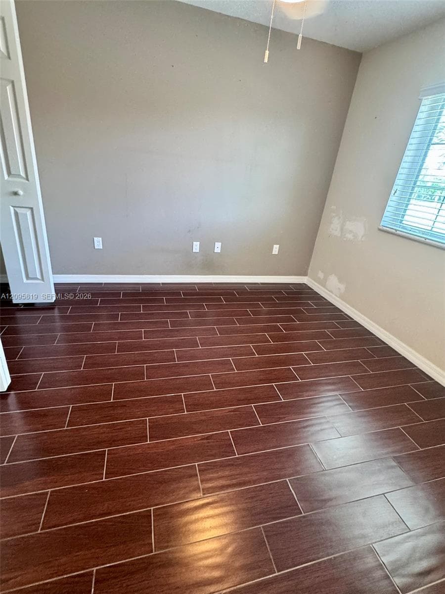 Wood-finish flooring, horizontal window blinds, and a ceiling-mounted light fixture with a pull chain
