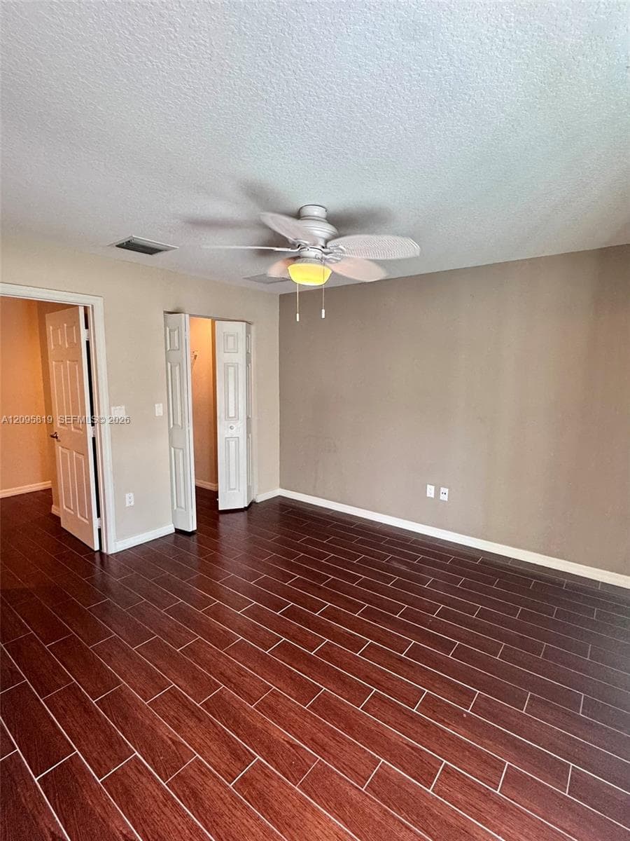 Room featuring wood-finish tile flooring, a neutral color palette, and a multi-blade ceiling fan with a center light fixture