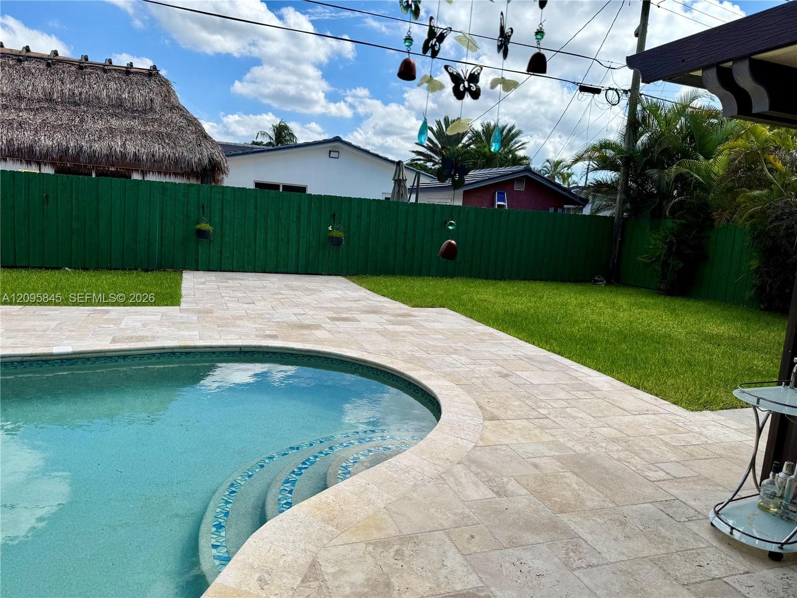 Private backyard featuring a swimming pool, integrated tiered steps, stone-finish decking, and solid-panel perimeter fencing