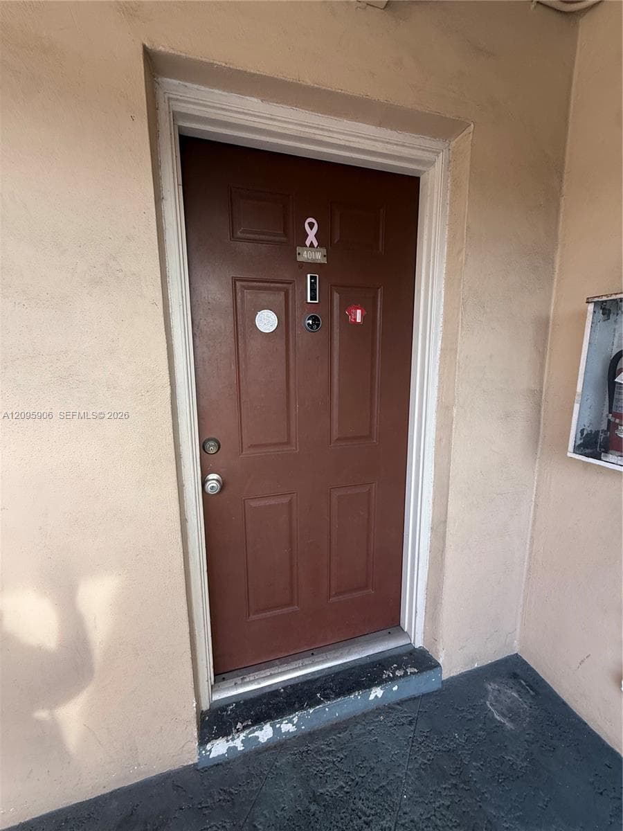 Solid-core brown entry door featuring a six-panel design, integrated doorbell camera, and brushed metallic hardware