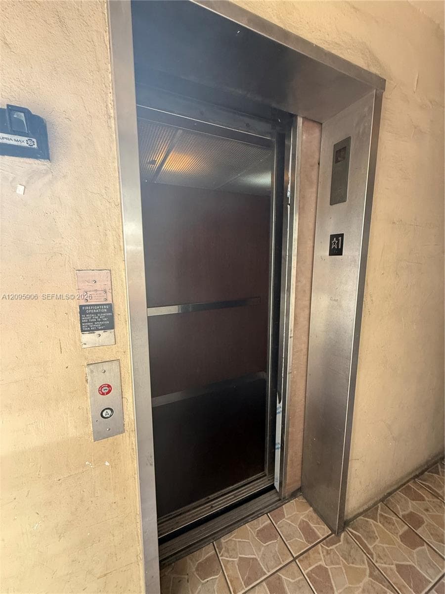 Elevator access featuring a brushed metal frame, stainless steel call station, and tiled flooring