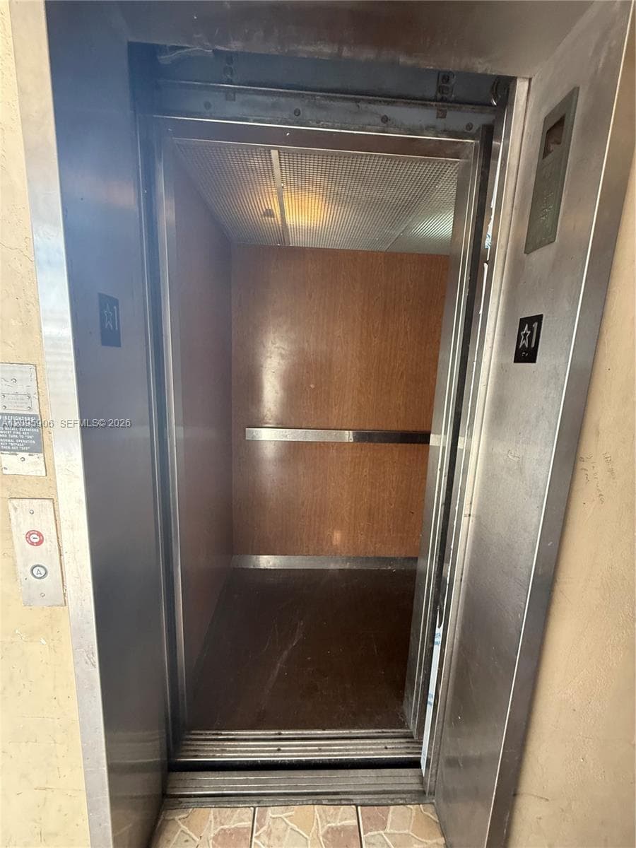 Elevator featuring brushed stainless steel door frame, wood-panelled interior walls, integrated handrail, and recessed ceiling lighting