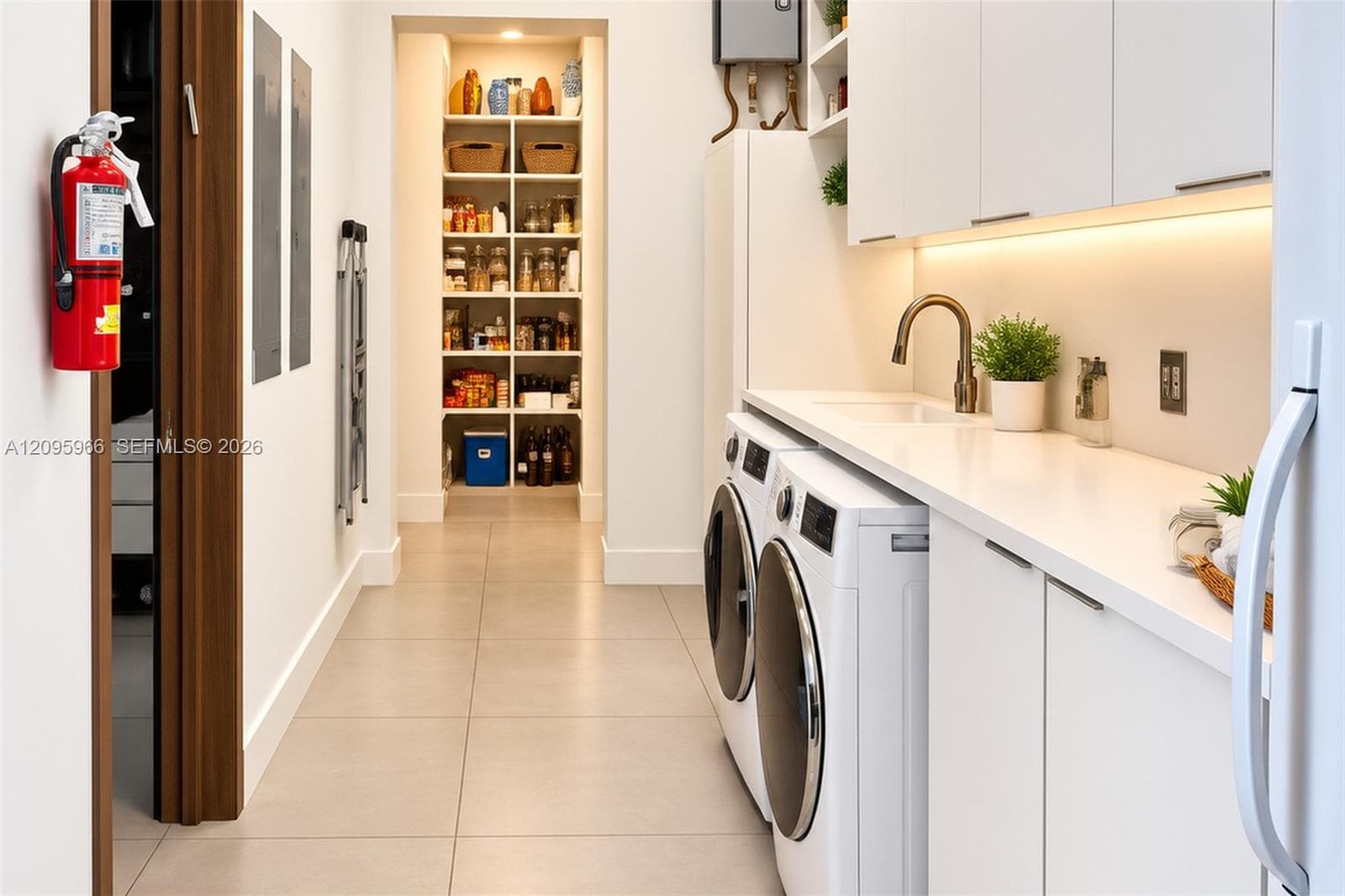 Utility room featuring white shaker-style cabinetry, solid-surface countertops, an integrated sink with a bronze-finish faucet, under-cabinet lighting, and built-in floor-to-ceiling pantry shelving