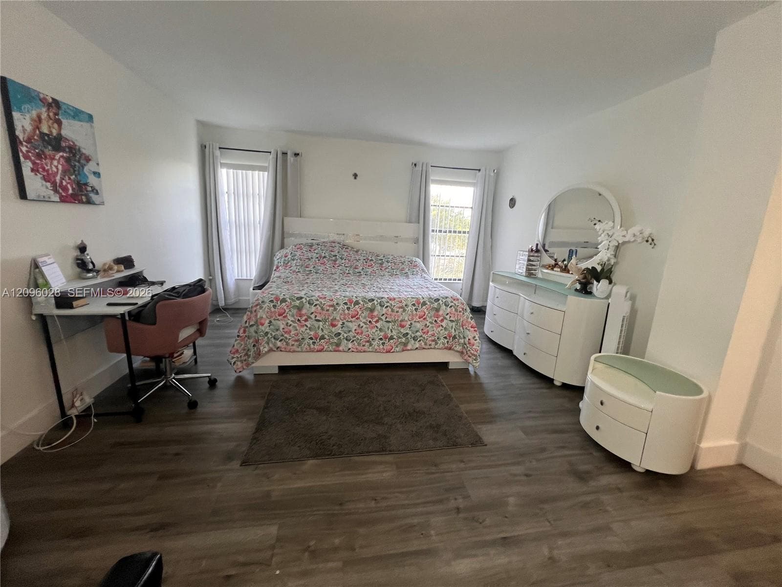 Room featuring wood-finish flooring, two windows, and neutral wall paint