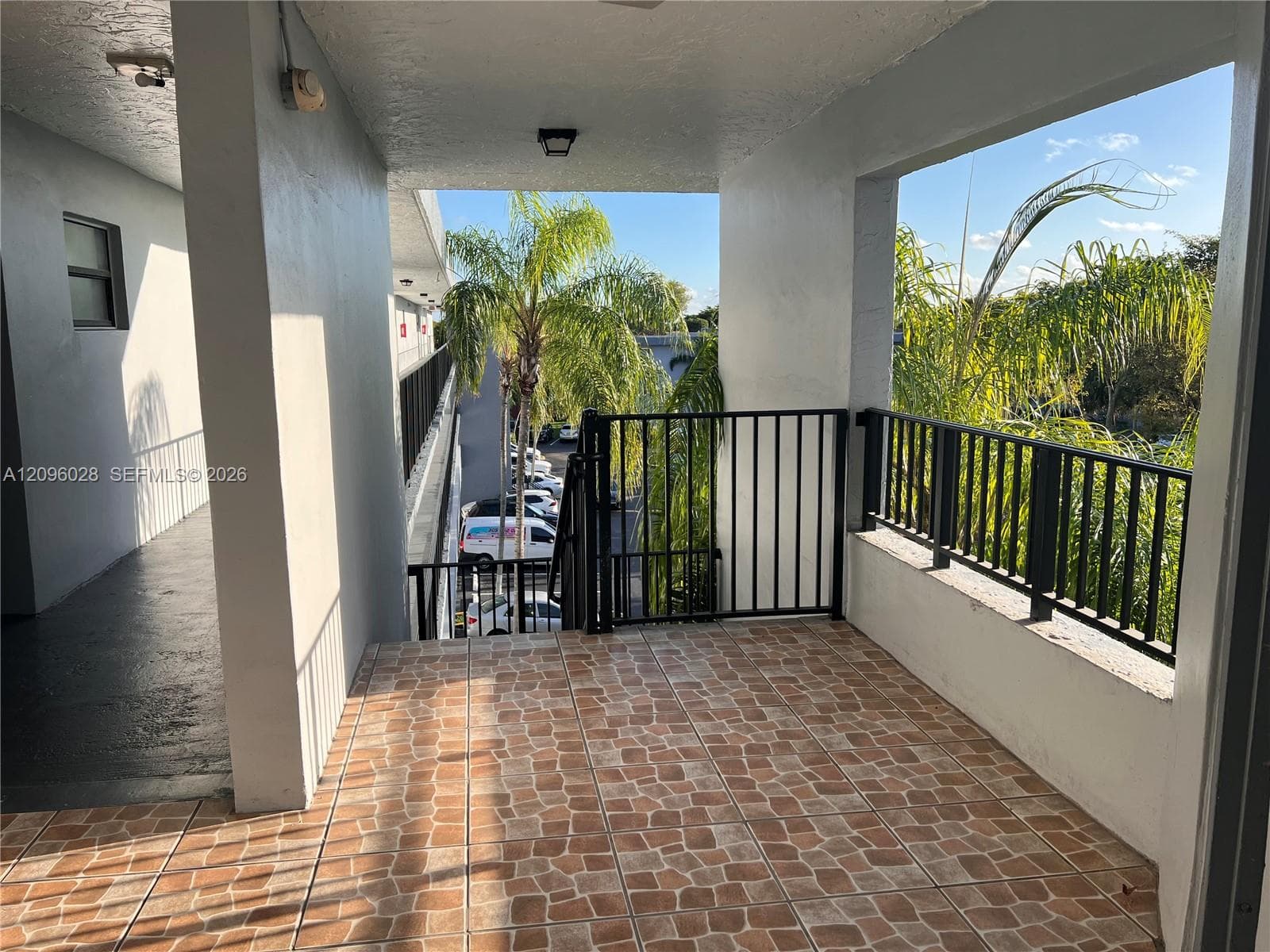 Covered exterior landing featuring stone-patterned tile flooring, black metal railing, and overhead lighting