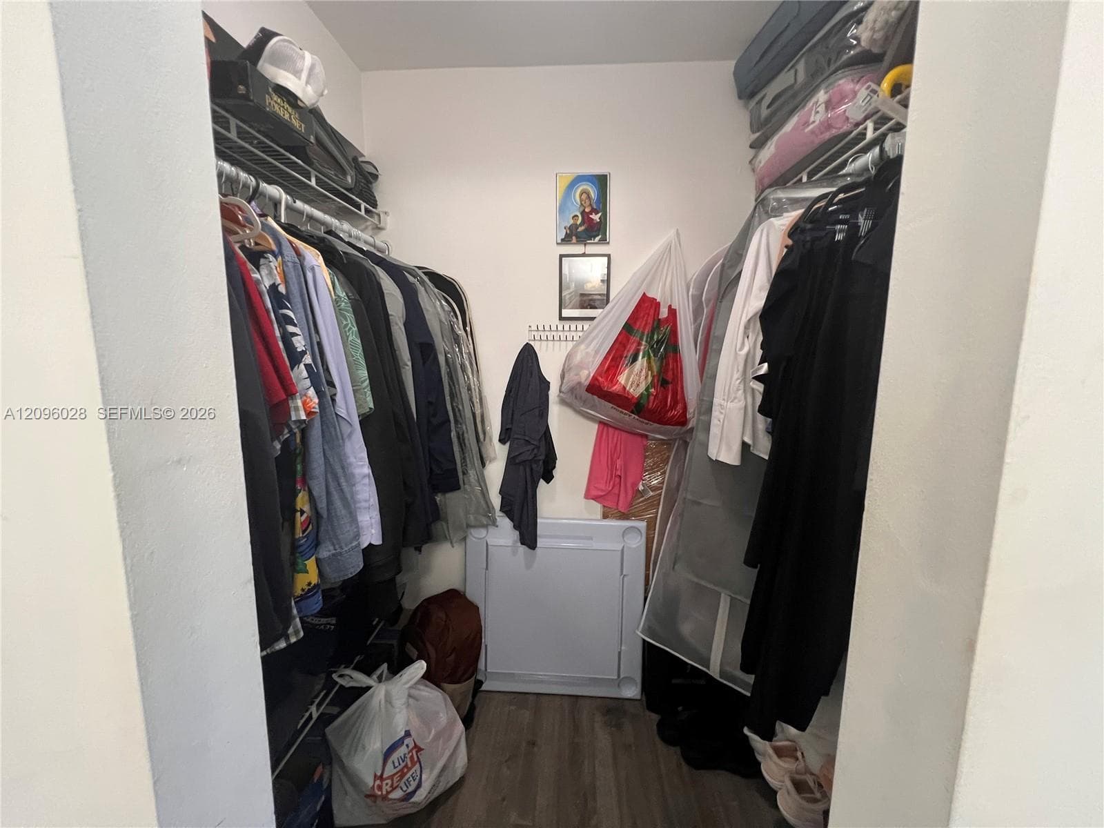 Walk-in closet featuring dual-level wire shelving and wood-finish flooring