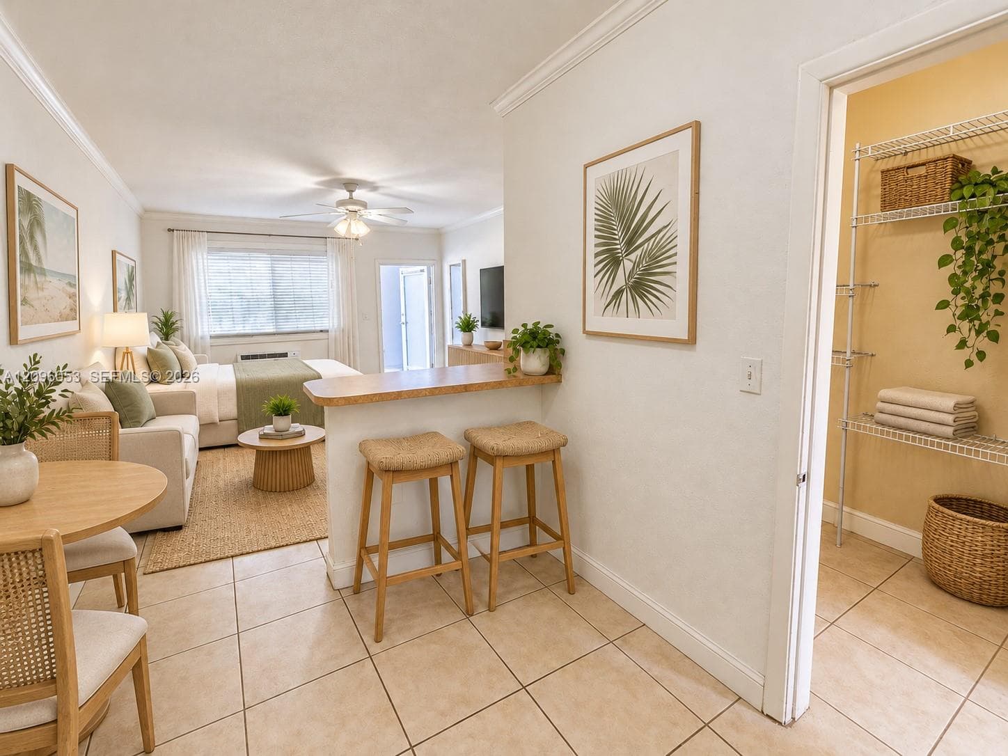 Open-concept floor plan featuring ceramic tile flooring, a breakfast bar with a wooden countertop, crown molding, and an interior closet with wire shelving
