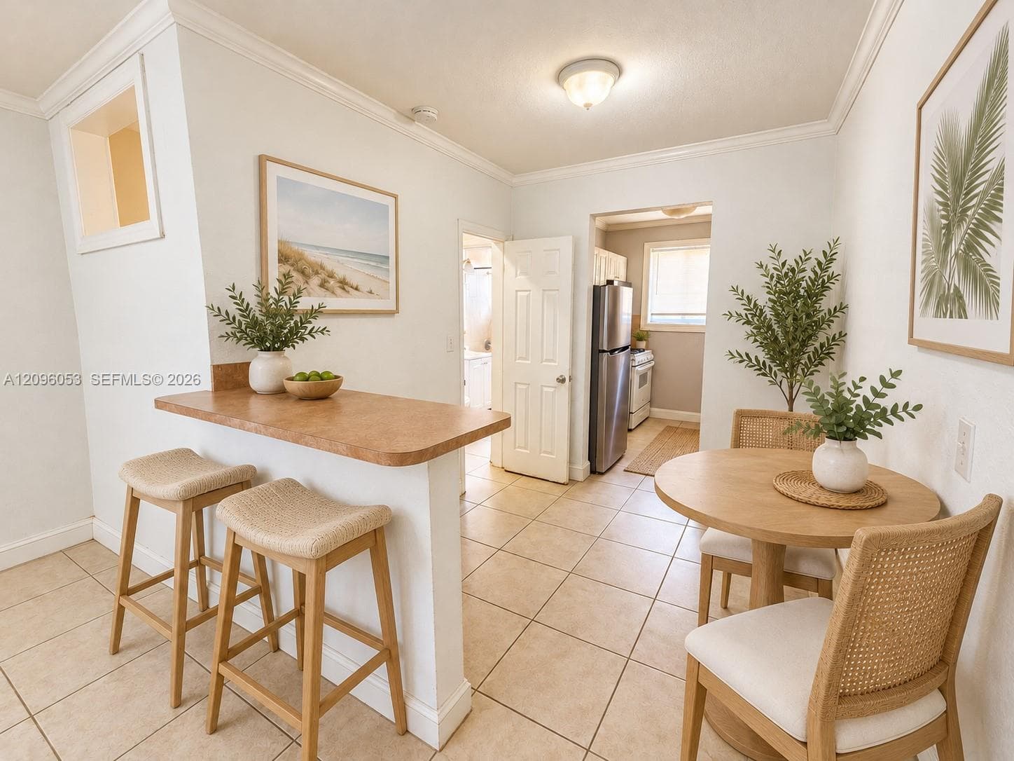 Kitchen area featuring a peninsula with a solid-surface countertop, ceramic tile flooring, and crisp white crown molding