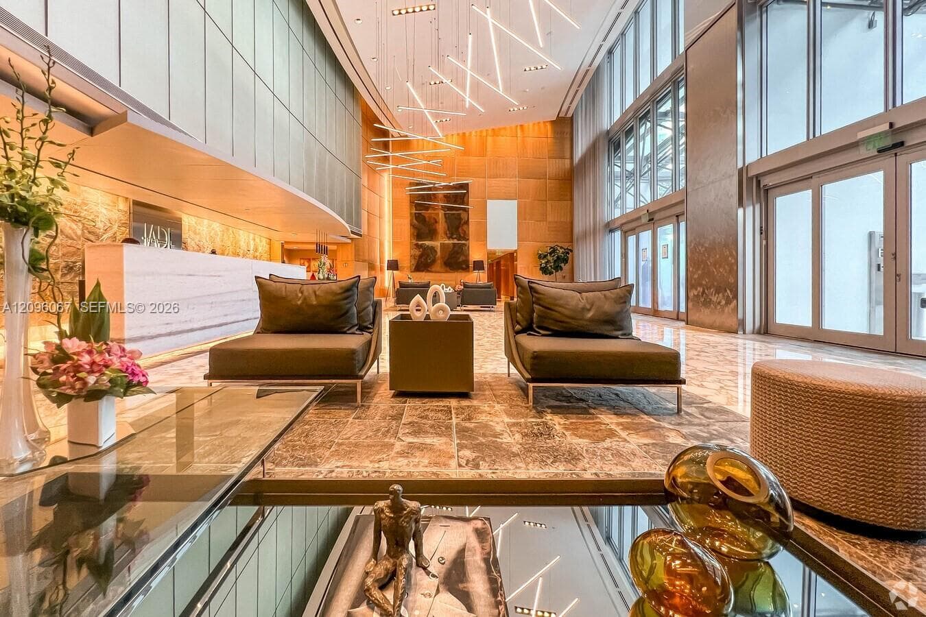 Stone tile flooring, high ceilings with recessed lighting, full-height glass paneling, and an elegant reception desk
