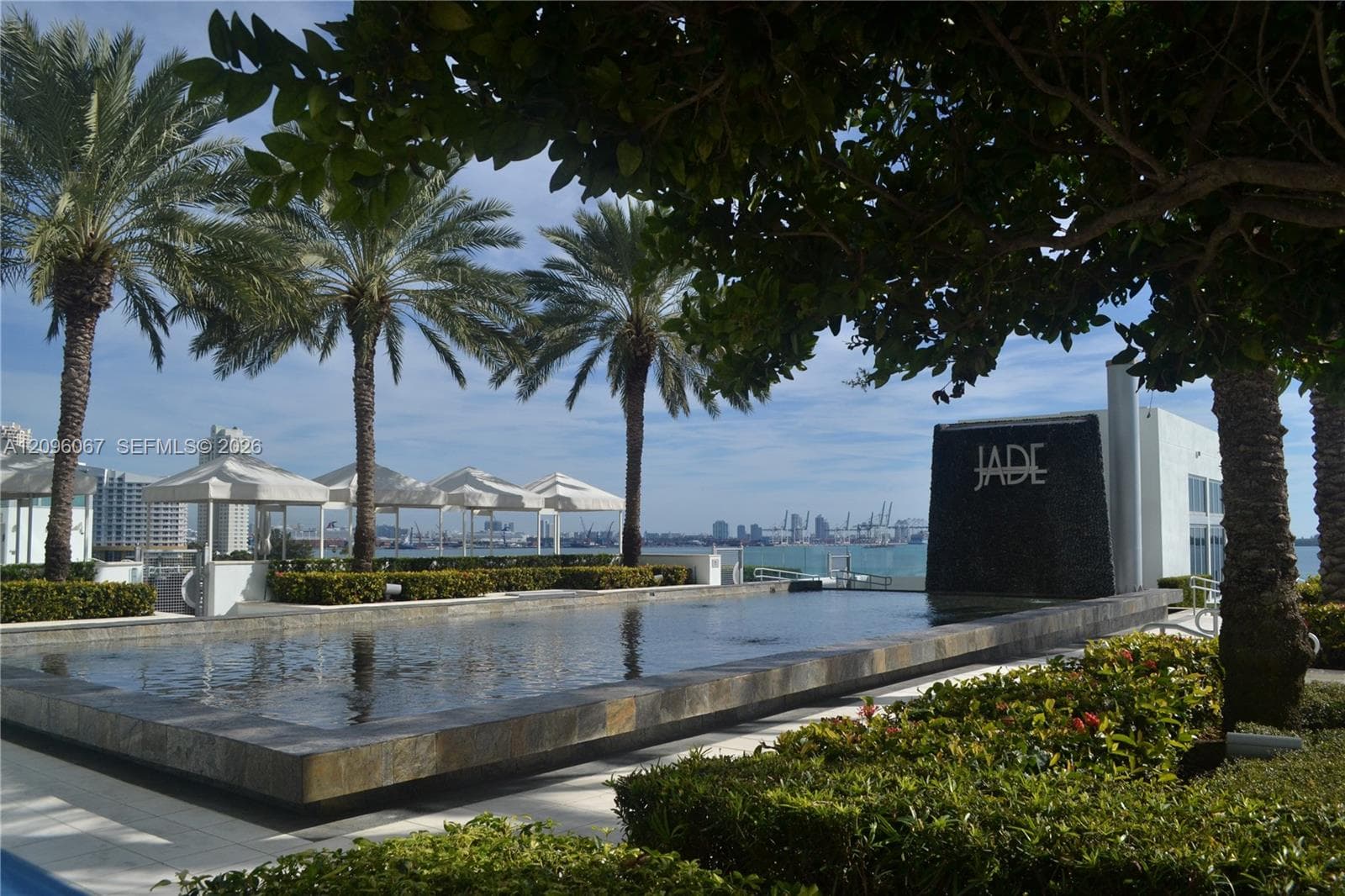 Expansive water feature with stone surround, complemented by manicured landscaping and mature palm trees