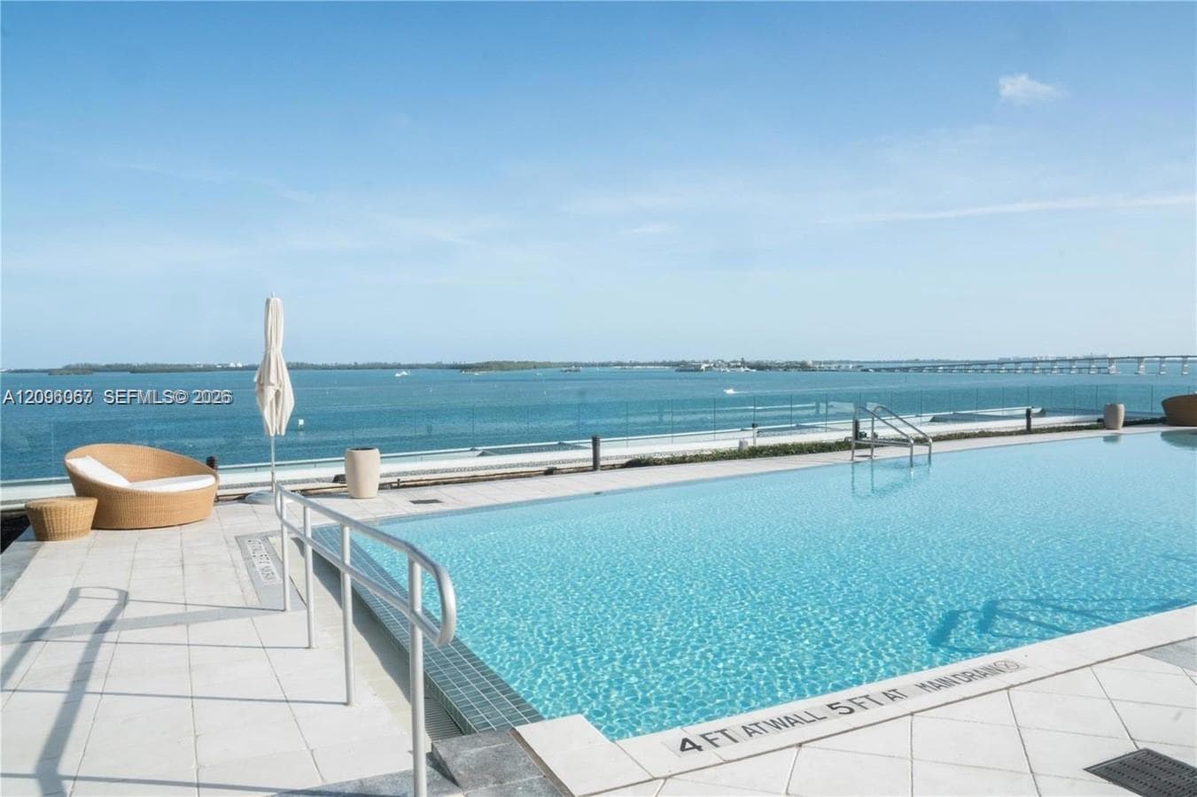 Expansive outdoor swimming pool with a surrounding tiled deck and glass perimeter railing