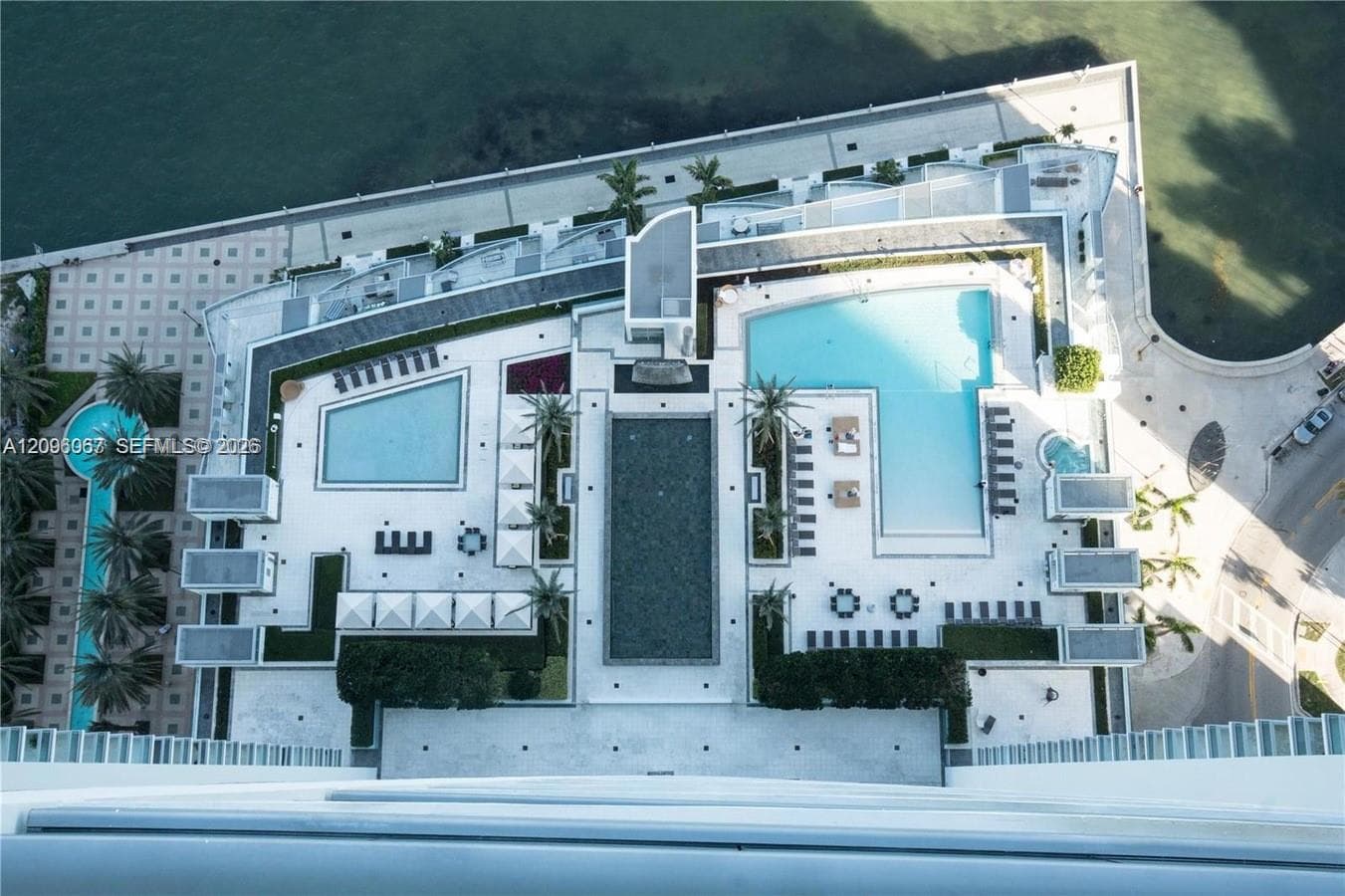 Multiple outdoor pools, paved sun decks, waterfront proximity, and mature palm trees