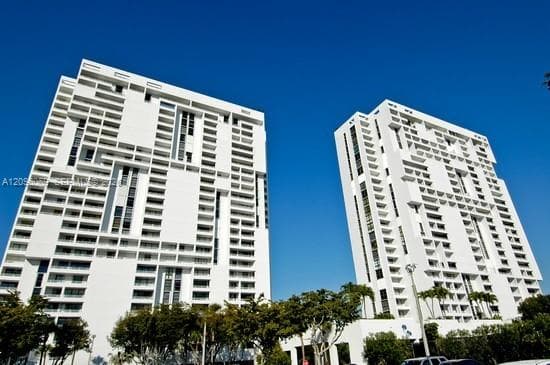 High-rise residential towers featuring distinctive grid-patterned white facades, recessed balconies, and vertical architectural detailing