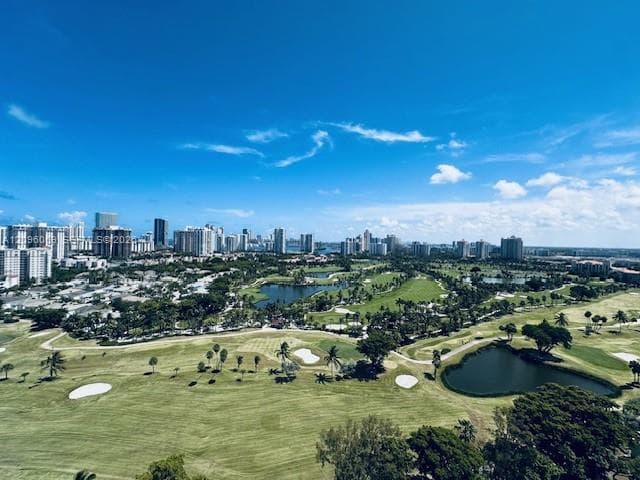 Panoramic landscape featuring a golf course, expansive greenery, water features, and a skyline backdrop