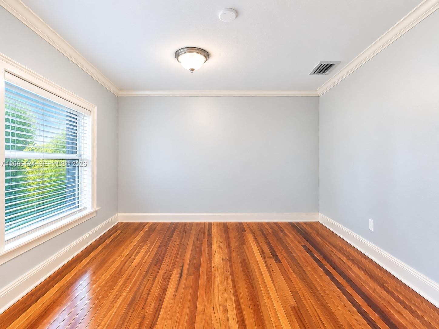 Interior room featuring wood-finish flooring, crown molding, a flush-mount ceiling light fixture, and large windows with horizontal blinds