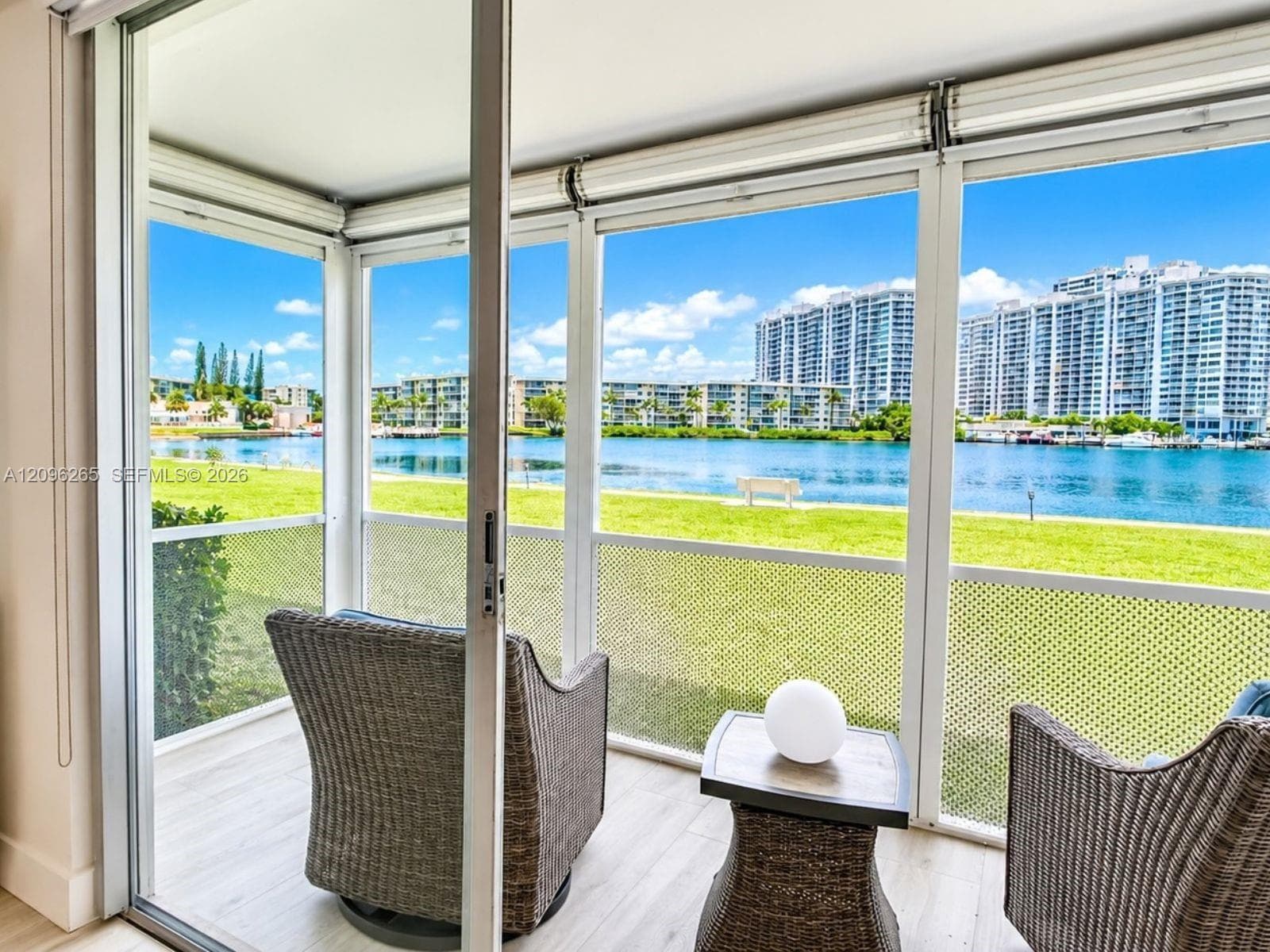 Enclosed balcony showcasing serene open water and lush landscape views.