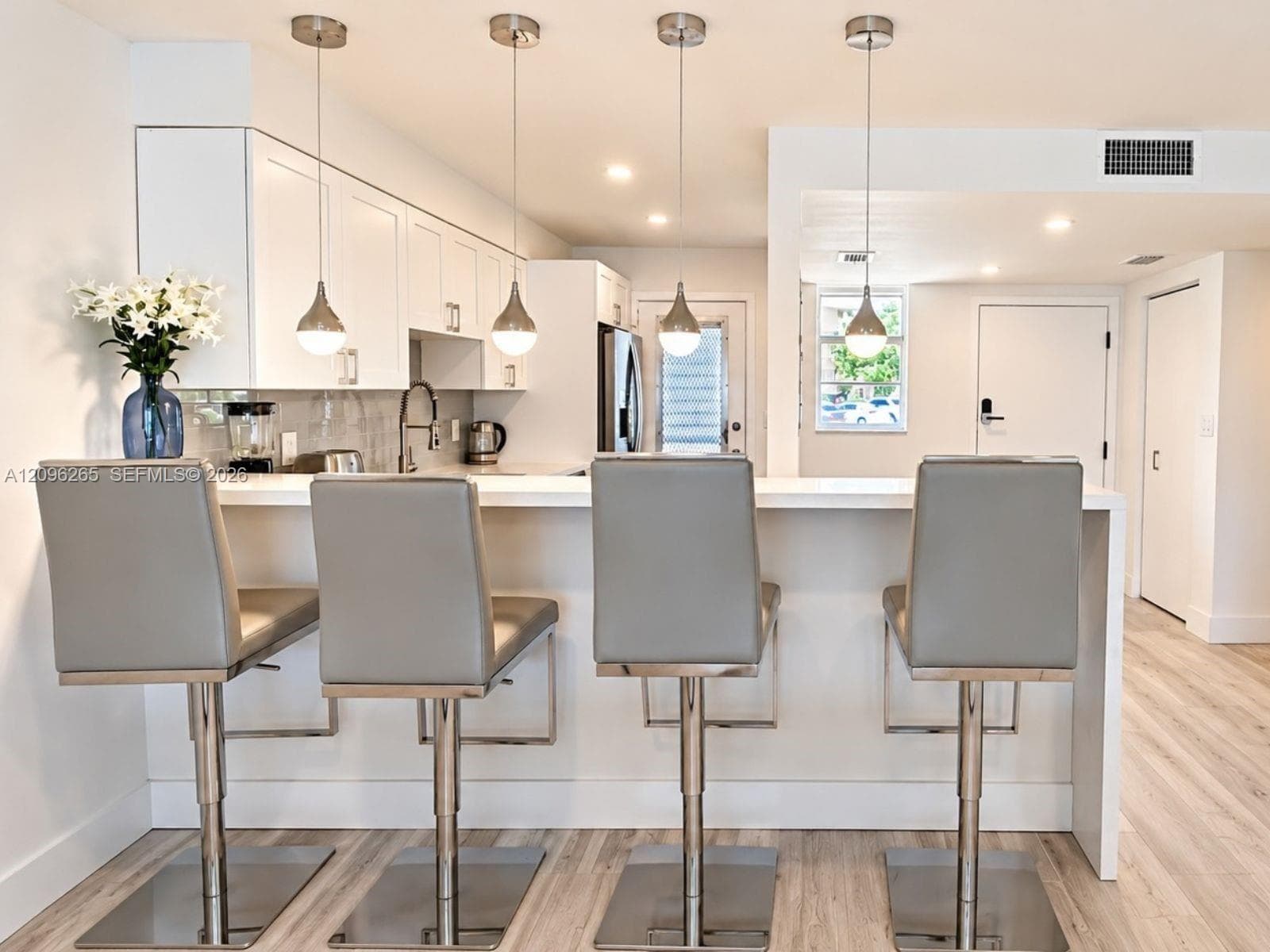 Alternate view of the renovated kitchen featuring breakfast bar counter seating and modern lighting.