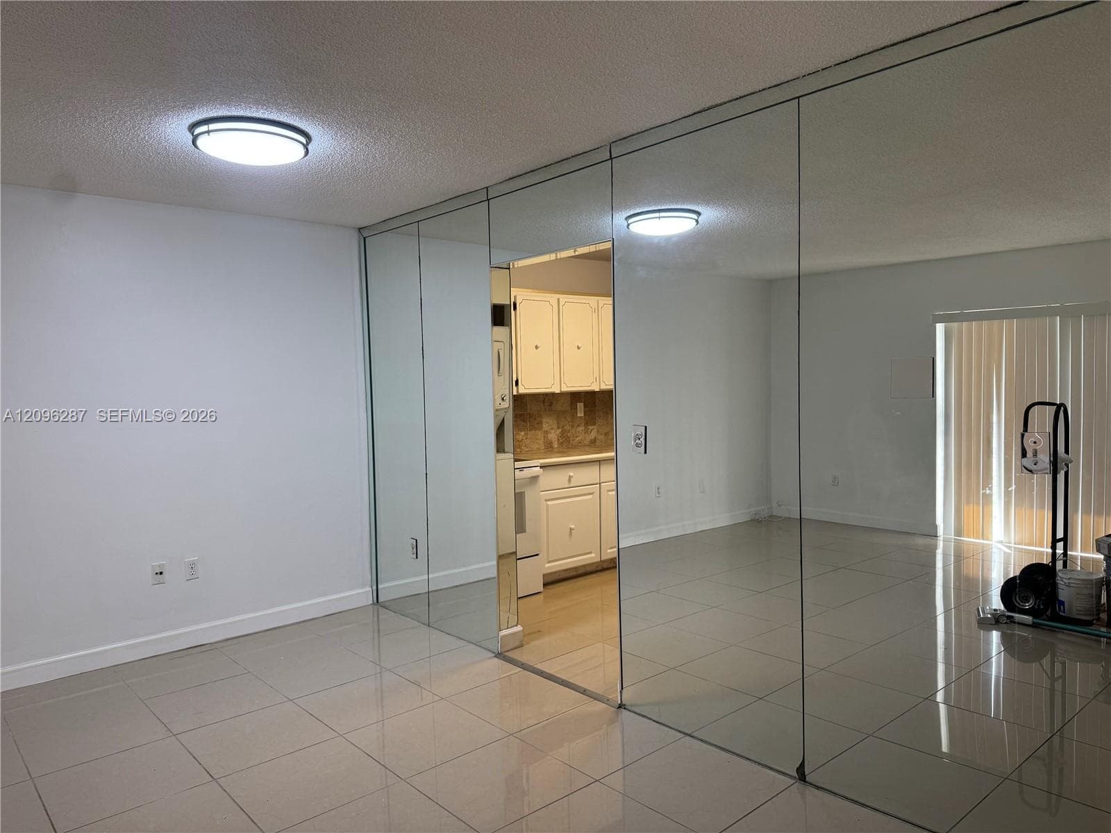Full-wall mirrored accent, polished tile flooring, and flush-mount ceiling lighting