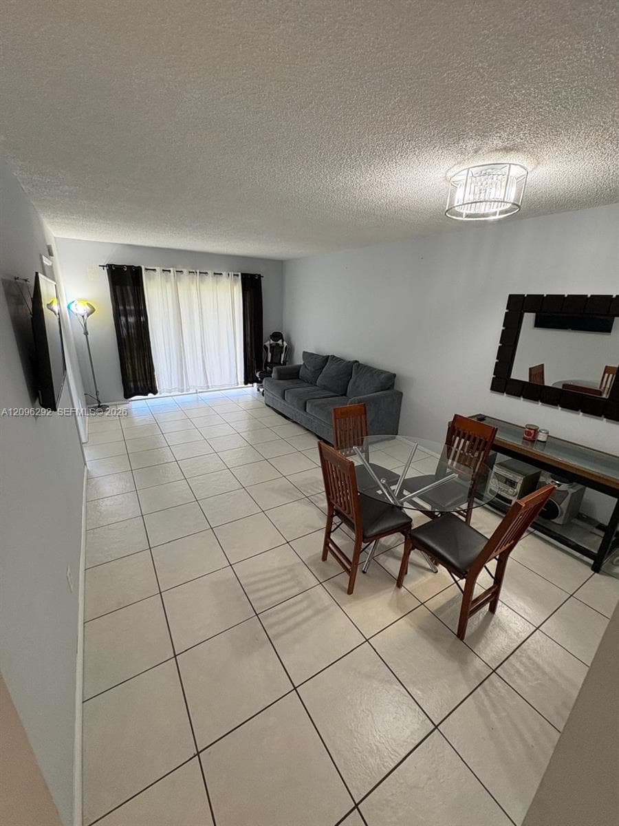 Large-format ceramic tile flooring, sliding glass patio doors, and a decorative semi-flush mount ceiling light fixture