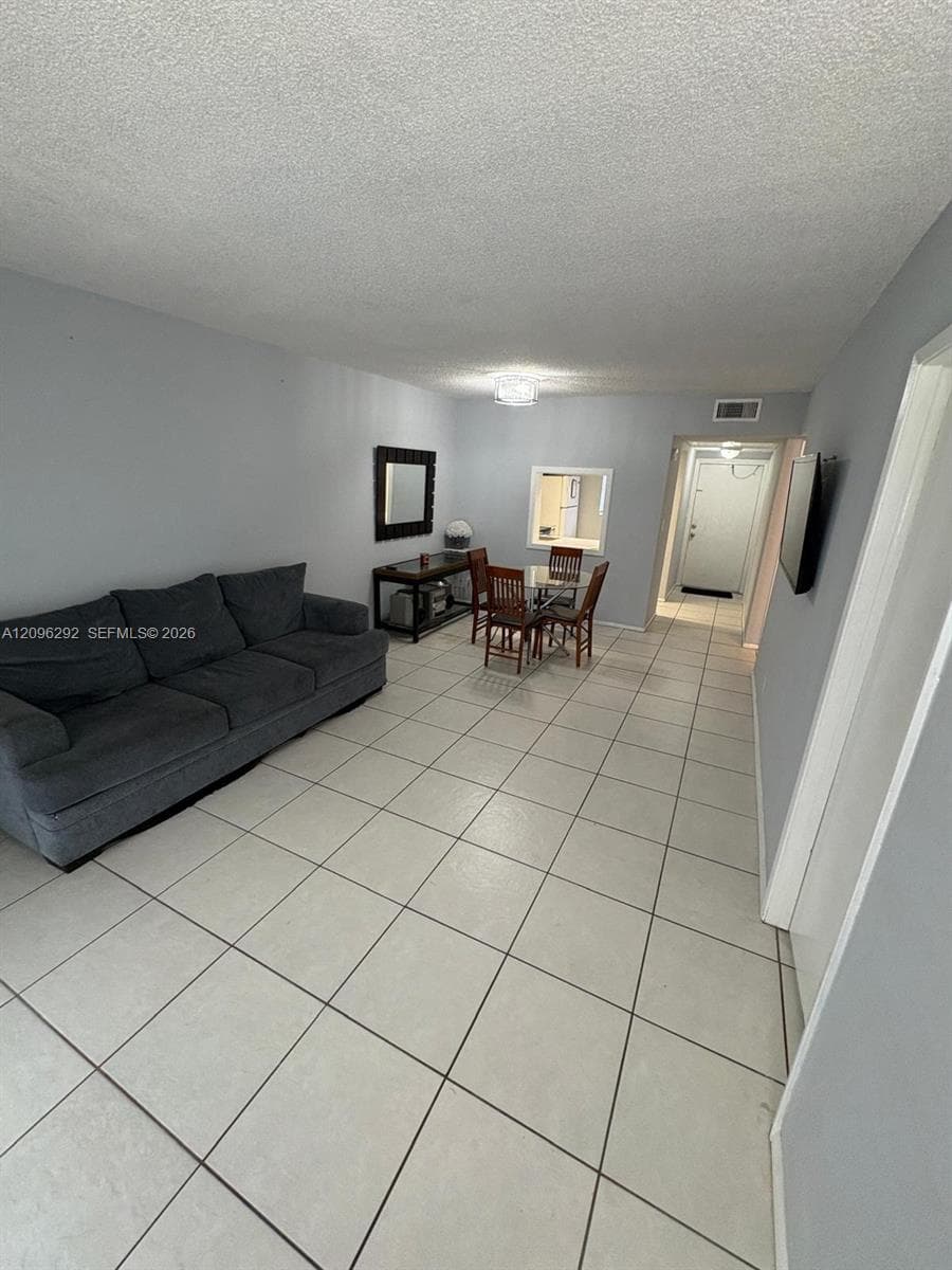 Large-format tile flooring, textured ceiling finish, and built-in service window