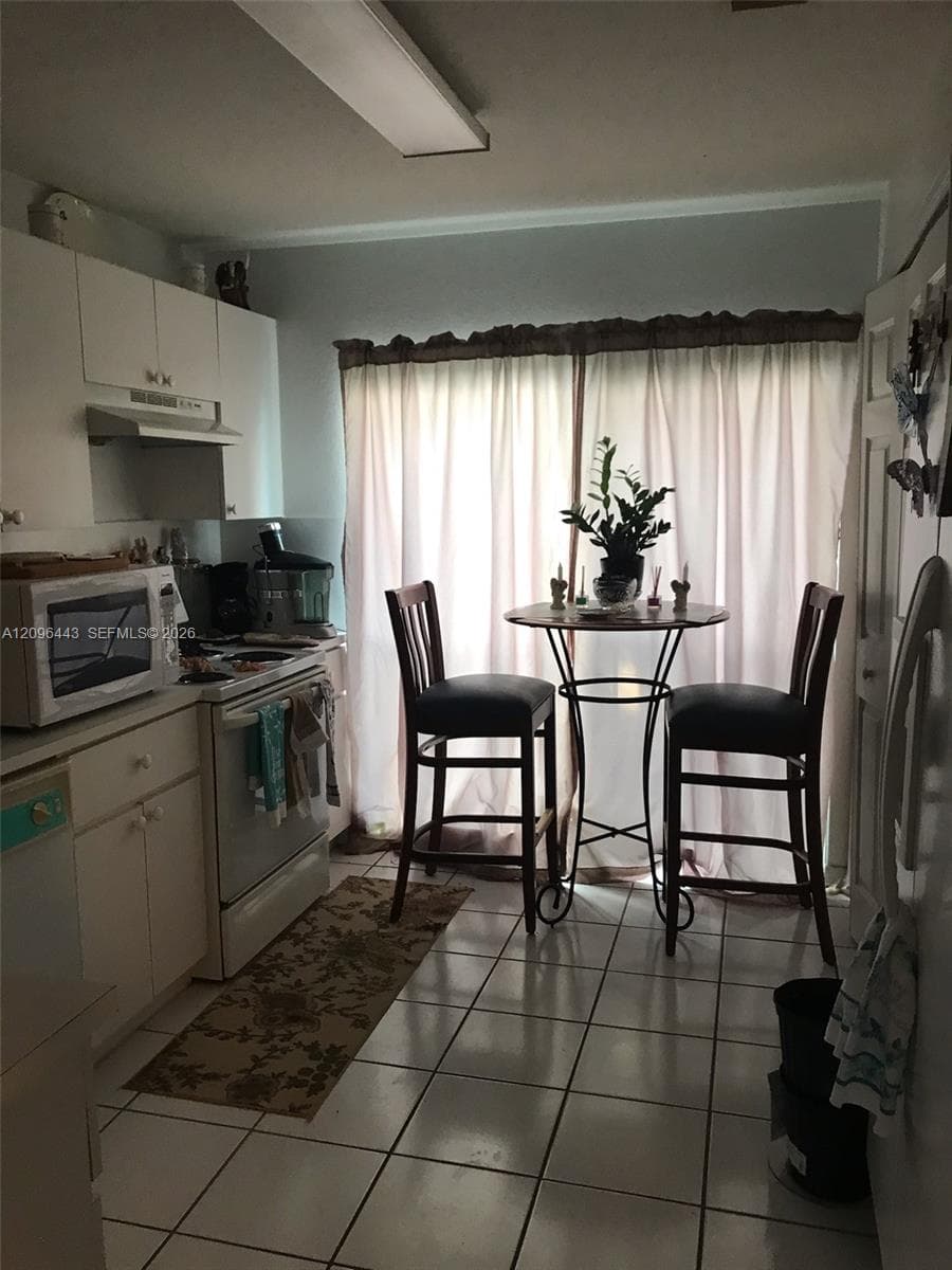 Kitchen featuring white cabinetry, ceramic tile flooring, and a large sliding glass door