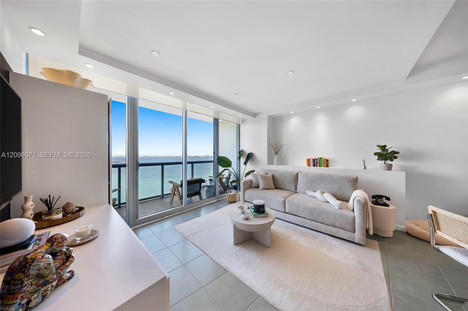 Living area featuring tile flooring, recessed lighting, built-in recessed wall shelving, and floor-to-ceiling glass sliding doors opening to a balcony