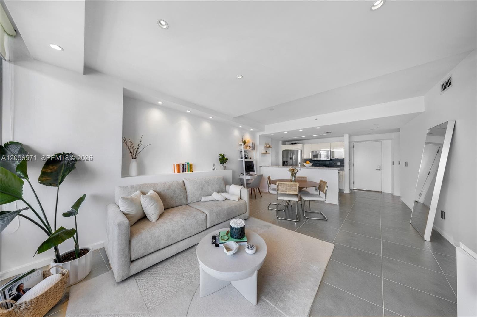Open-concept interior featuring large-format tile flooring, recessed ceiling lighting, and a built-in wall niche with integrated accent lighting