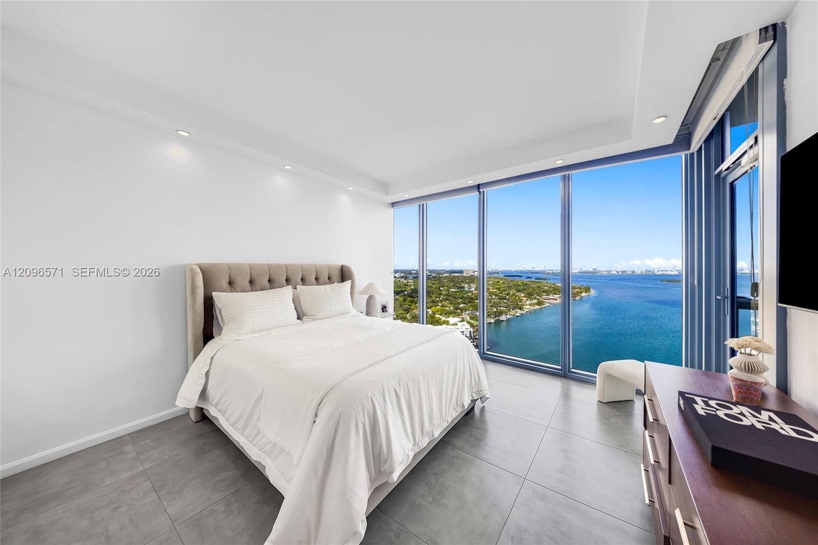 Floor-to-ceiling windows featuring panoramic water and landscape exposure, complemented by neutral tile flooring and recessed lighting