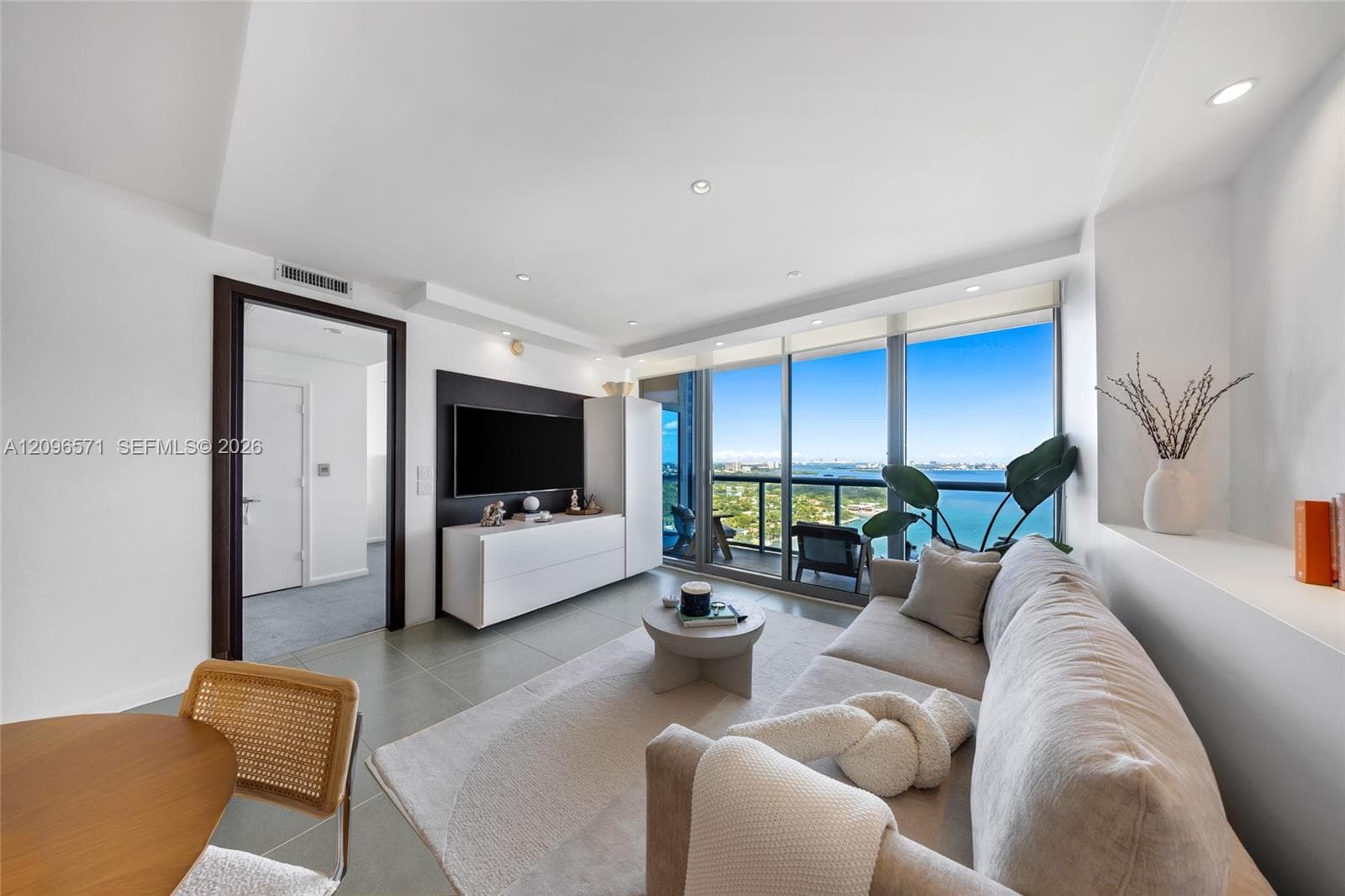 Floor-to-ceiling glass windows, recessed lighting, tile flooring, and integrated wall-mounted media panel