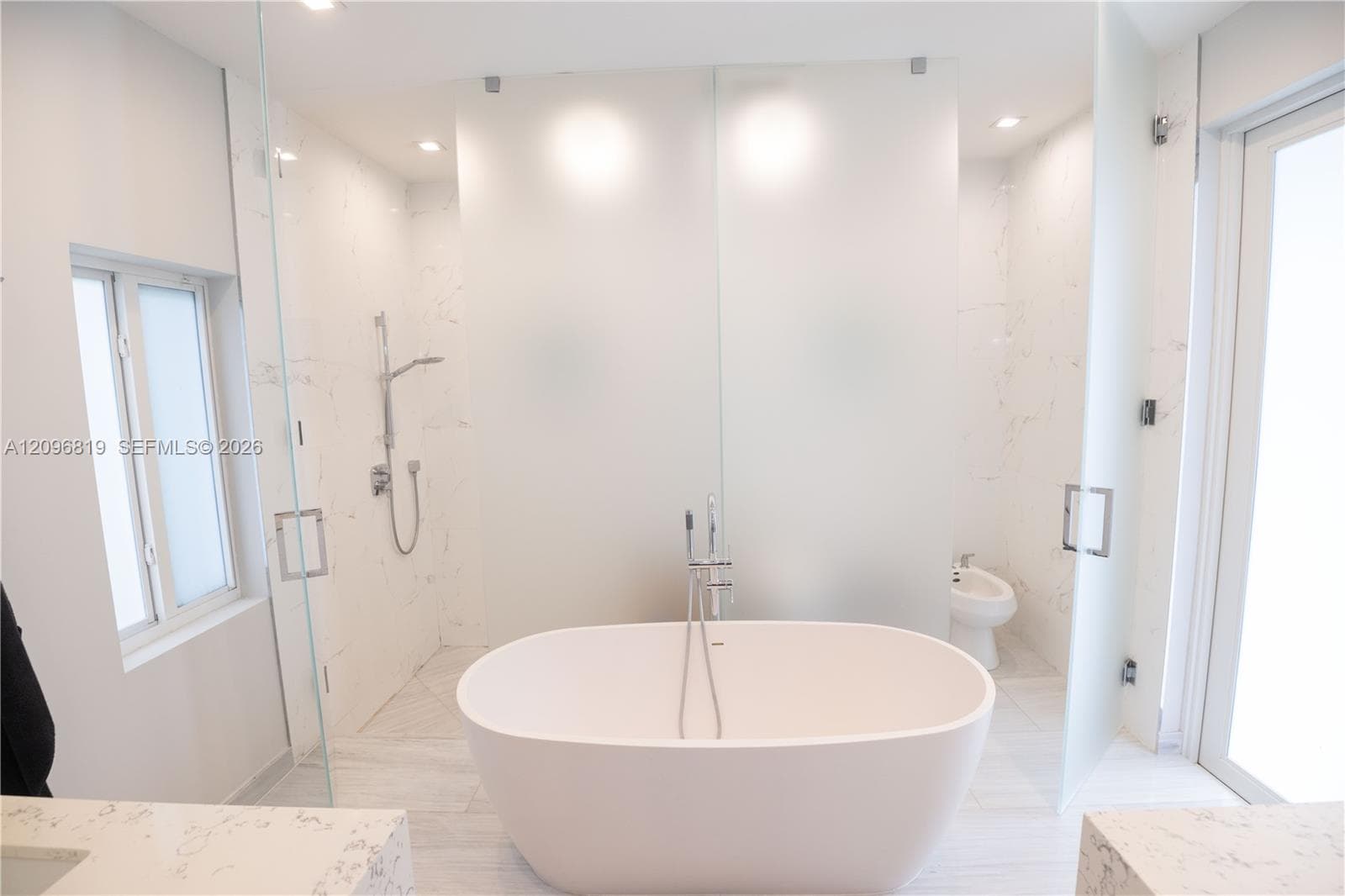 Spa Inspired Primary Bathroom featuring a freestanding stone soaking tub and oversized glass-enclosed walk in shower. And a Private enclosed water closet with toilet and bidet.