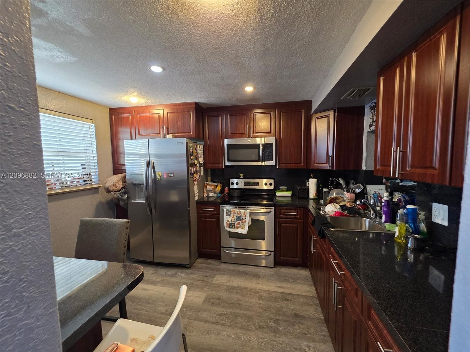 Updated kitchen featuring rich wood cabinetry, granite-like countertops, stainless steel appliances, and ample cabinet and counter space.