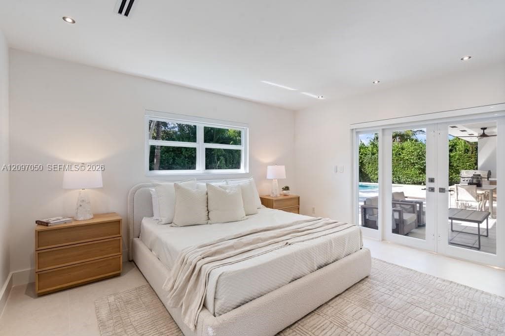 Neutral-toned room featuring recessed lighting, large-format tile flooring, and white-framed glass doors providing exterior access
