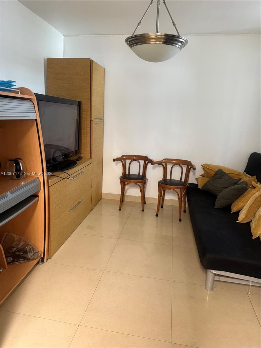 Interior space featuring large-format ceramic tile flooring, built-in floor-to-ceiling cabinetry with wood finish, and a semi-flush mount bowl pendant light fixture
