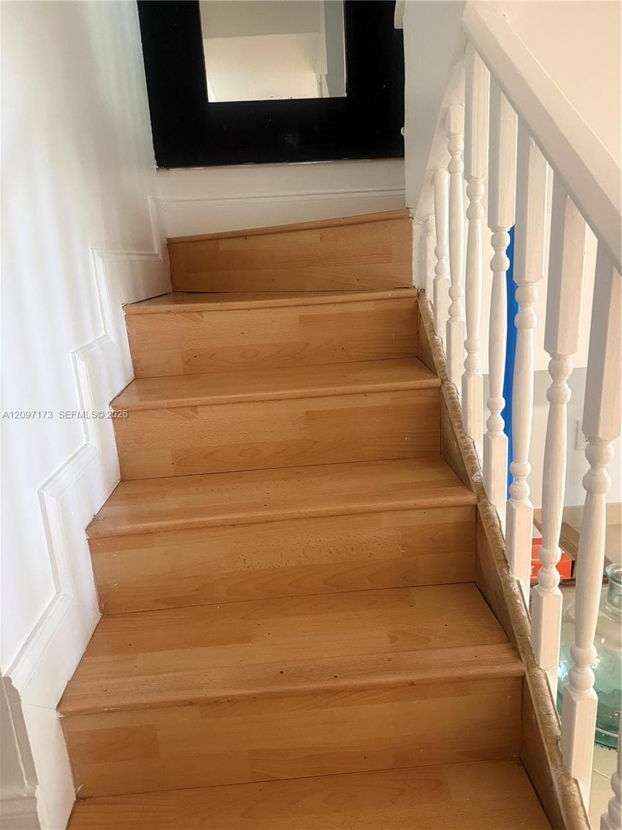 Staircase featuring wood-finish treads and white painted balusters with a matching handrail