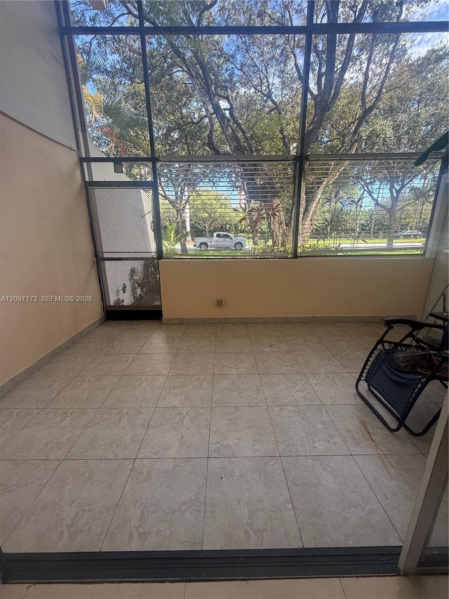 Enclosed porch featuring large-format ceramic tile flooring, floor-to-ceiling metal-framed screening, and a dedicated screen door