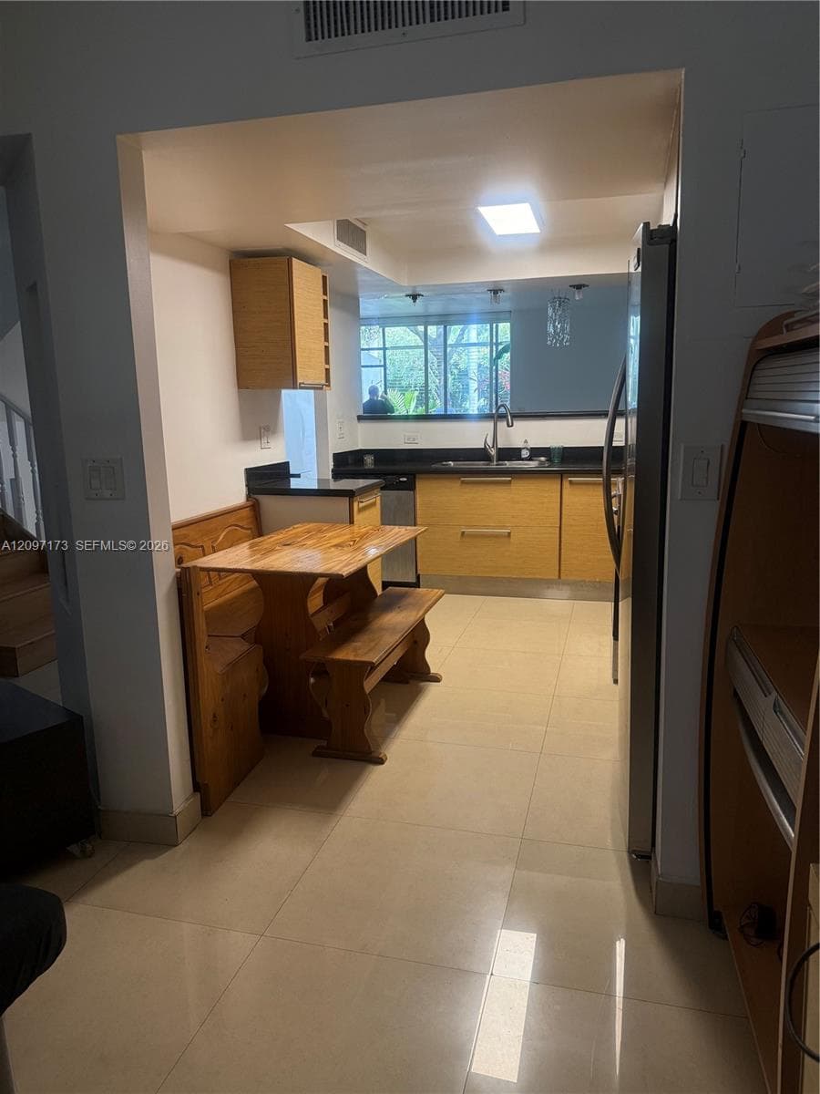 Kitchen featuring light-finish cabinetry, dark solid-surface countertops, tile flooring, and integrated ceiling lighting