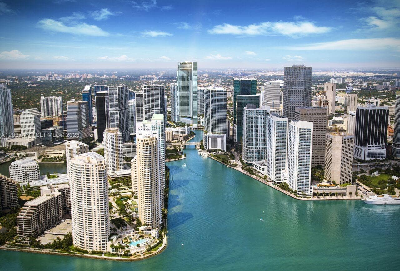 Aerial perspective of a high-density urban corridor featuring a central river, expansive waterfront exposure, glass-façade high-rise structures, and integrated deep-water boat docking areas